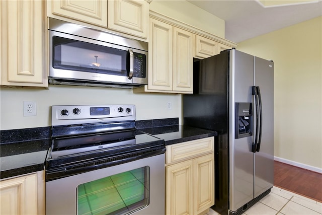 180 Grace Chapel Unit 107, Blue Eye, MO 65611 - kitchen with stainless steel appliances, cream cabinetry, dark stone countertops, and light wood-type flooring