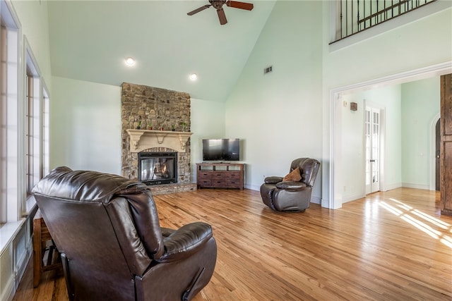 living room featuring a fireplace, light hardwood / wood-style floors, ceiling fan, and high vaulted ceiling