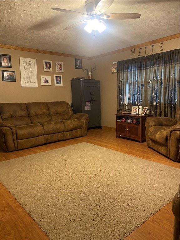 living room with ceiling fan, a textured ceiling, and wood-type flooring