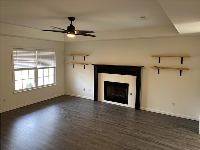 unfurnished living room with ceiling fan, dark hardwood / wood-style floors, and a tile fireplace