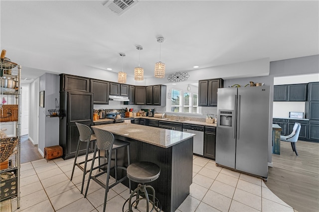 kitchen featuring appliances with stainless steel finishes, dark brown cabinetry, pendant lighting, light hardwood / wood-style flooring, and a kitchen island