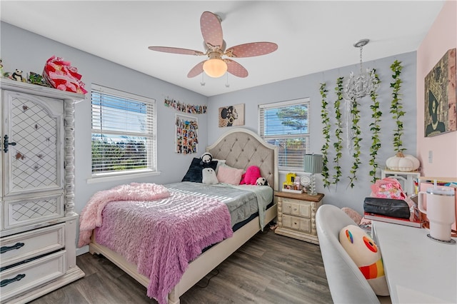 bedroom with ceiling fan with notable chandelier and dark hardwood / wood-style floors