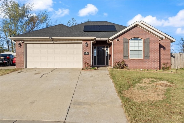 single story home with solar panels, a front yard, and a garage