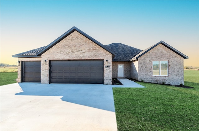 view of front of property with a garage and a yard