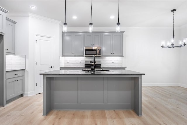 kitchen featuring tasteful backsplash, gray cabinetry, sink, pendant lighting, and dark stone countertops