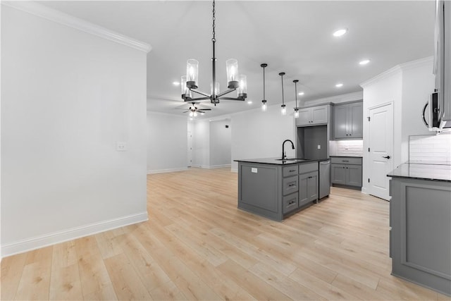 kitchen with decorative backsplash, stainless steel appliances, gray cabinets, hanging light fixtures, and an island with sink