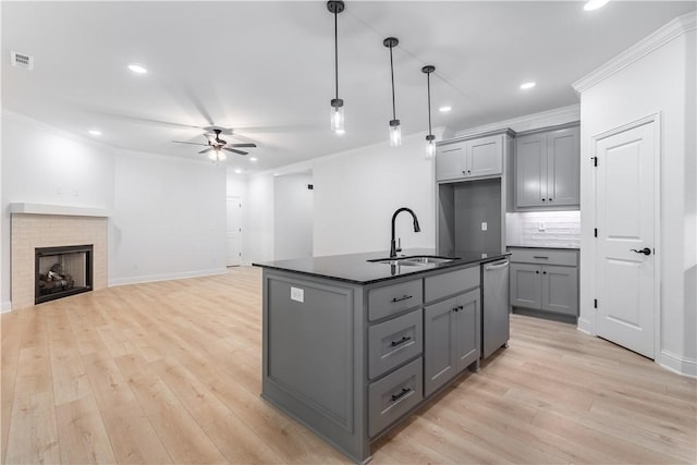 kitchen with gray cabinetry, ceiling fan, sink, decorative light fixtures, and a kitchen island with sink