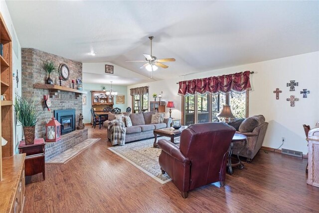 living room with ceiling fan with notable chandelier, dark hardwood / wood-style flooring, a fireplace, and lofted ceiling