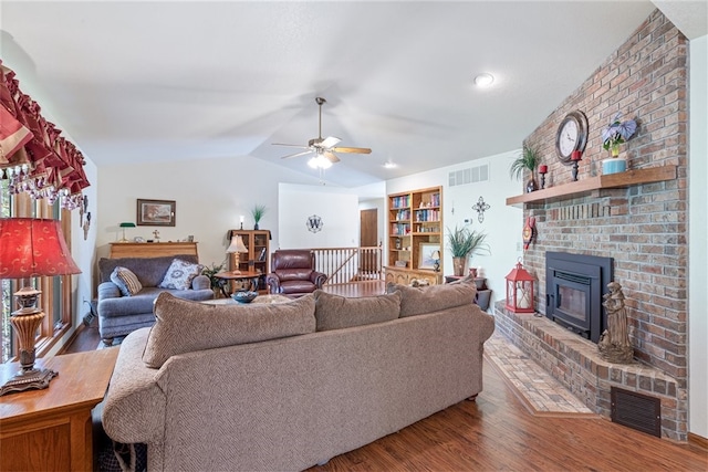 living room featuring ceiling fan, wood-type flooring, a fireplace, and vaulted ceiling