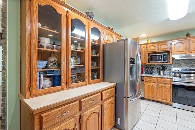 kitchen with light tile patterned floors, decorative backsplash, a textured ceiling, and appliances with stainless steel finishes