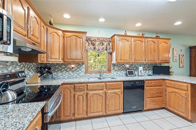 kitchen with light tile patterned flooring, appliances with stainless steel finishes, light stone countertops, and sink