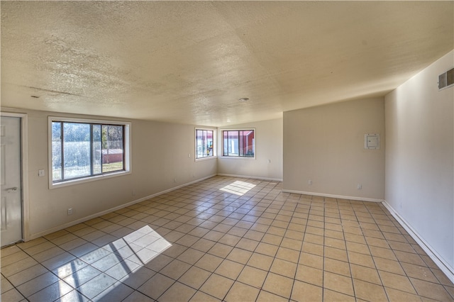 tiled empty room featuring lofted ceiling and a textured ceiling