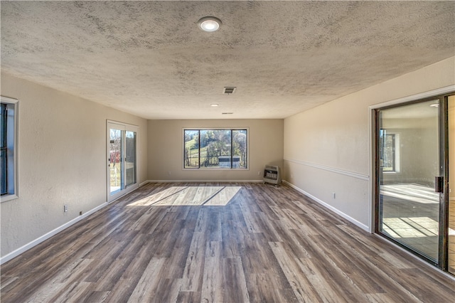 spare room with dark hardwood / wood-style floors, a textured ceiling, and heating unit