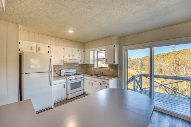 kitchen featuring white cabinets, hardwood / wood-style floors, sink, backsplash, and white appliances