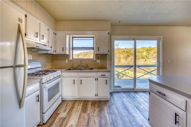 kitchen featuring white cabinetry, decorative backsplash, sink, light hardwood / wood-style floors, and white appliances