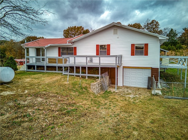 back of property featuring a garage, a lawn, and a wooden deck