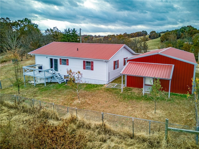 rear view of property featuring an outbuilding, a lawn, and a wooden deck