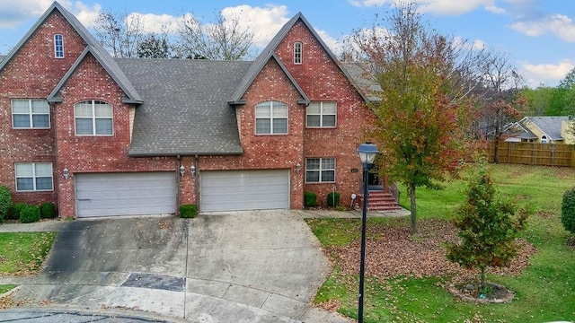 view of front of house featuring roof with shingles, brick siding, fence, driveway, and a front lawn