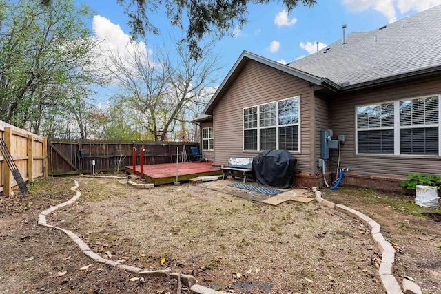 back of house with a shingled roof, fence, and a wooden deck