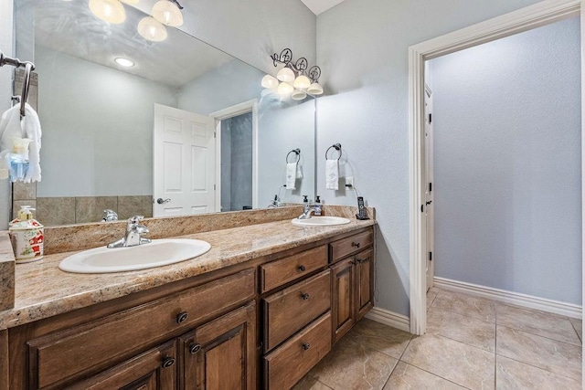 full bath with double vanity, baseboards, a sink, and tile patterned floors