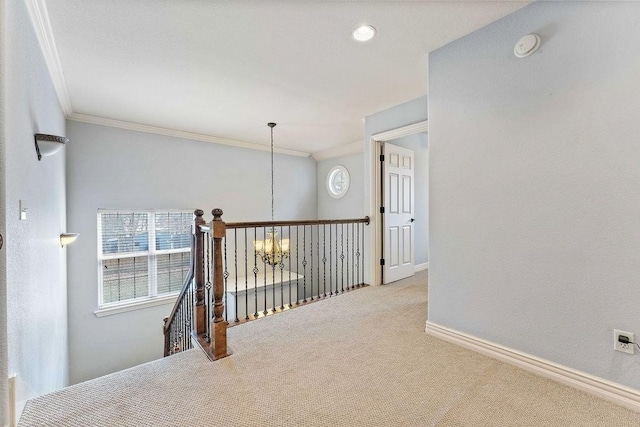 hall with baseboards, an upstairs landing, crown molding, carpet flooring, and a notable chandelier