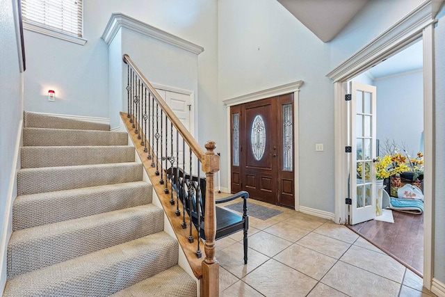 entrance foyer featuring a towering ceiling, baseboards, stairway, and light tile patterned flooring