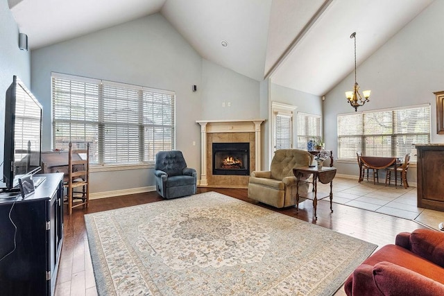 living area with a fireplace, a chandelier, a wealth of natural light, and wood finished floors