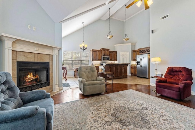 living room featuring baseboards, a tiled fireplace, visible vents, and wood finished floors