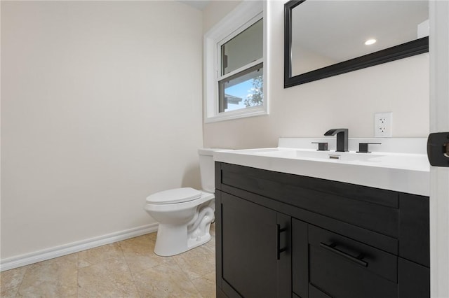 bathroom with toilet, vanity, and baseboards