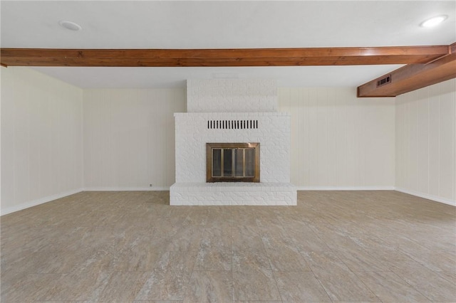 unfurnished living room with beamed ceiling and a fireplace