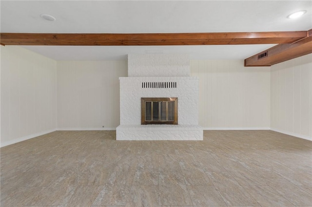 unfurnished living room with beam ceiling, wood finished floors, and a brick fireplace