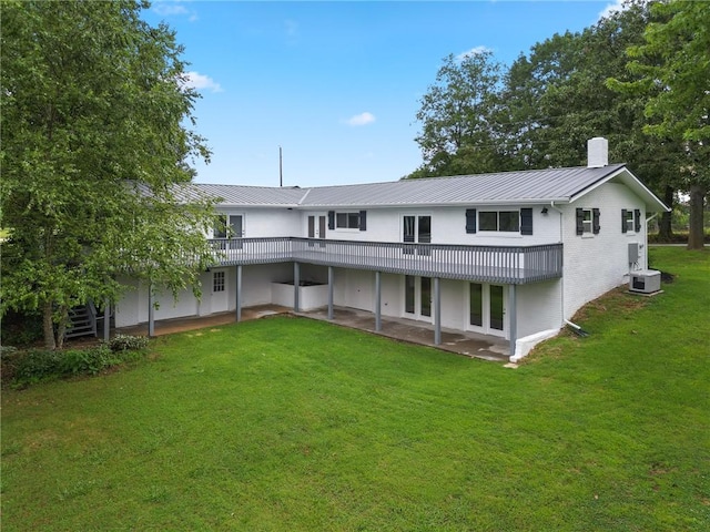 back of property featuring a standing seam roof, a patio area, metal roof, a yard, and a chimney
