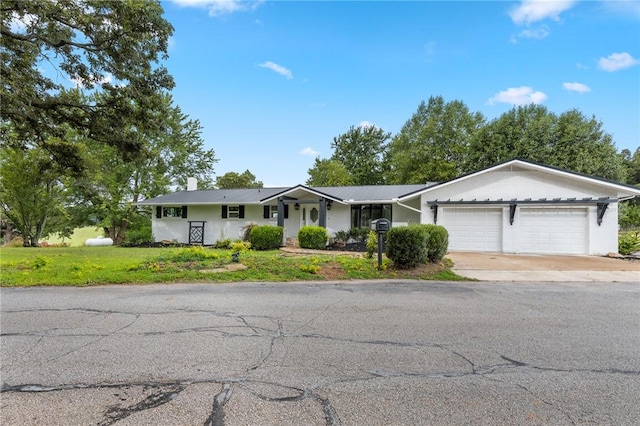 ranch-style house with driveway, a chimney, a front lawn, and a garage