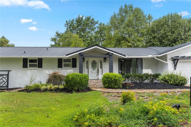 ranch-style home featuring metal roof, a front yard, an attached garage, and brick siding