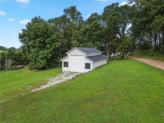 view of yard with a detached garage, an outbuilding, and driveway