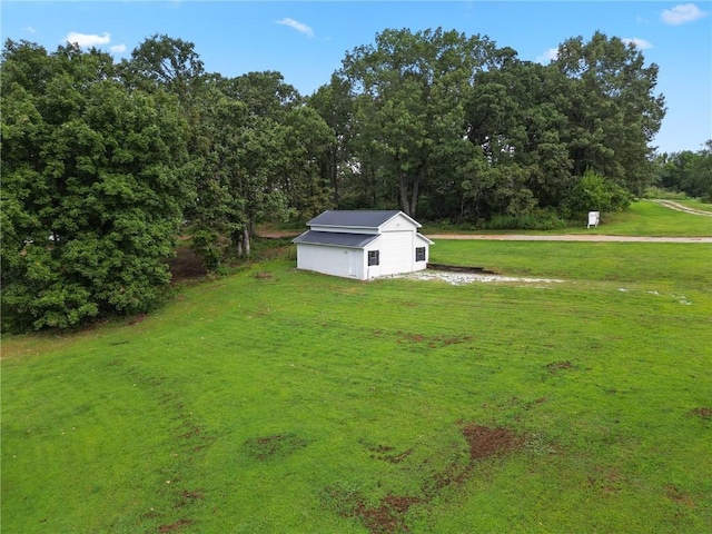 view of yard featuring an outdoor structure and a wooded view