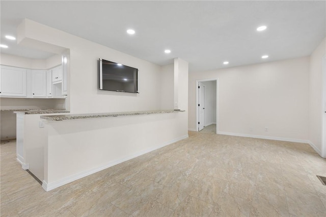 interior space with light stone counters, white cabinetry, and kitchen peninsula