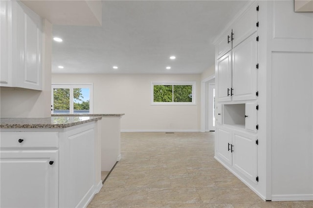 kitchen featuring light stone countertops, a wealth of natural light, white cabinetry, and recessed lighting