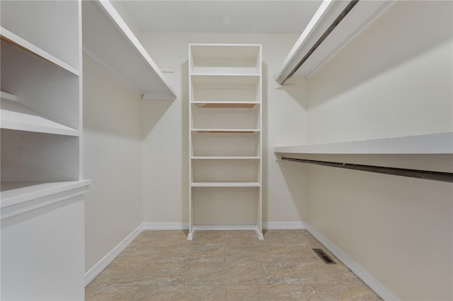 walk in closet with stone finish floor and visible vents