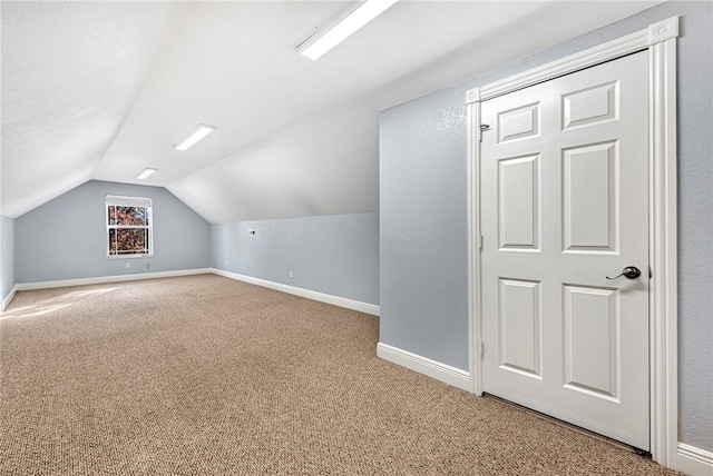 additional living space with lofted ceiling, carpet floors, and a textured ceiling