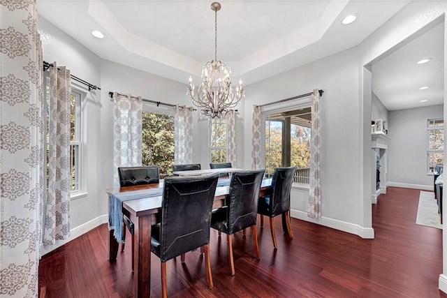 dining room with a raised ceiling, dark hardwood / wood-style floors, and a notable chandelier