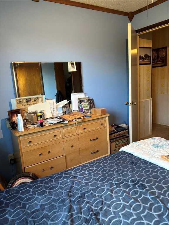 carpeted bedroom with wood walls, a textured ceiling, and ornamental molding