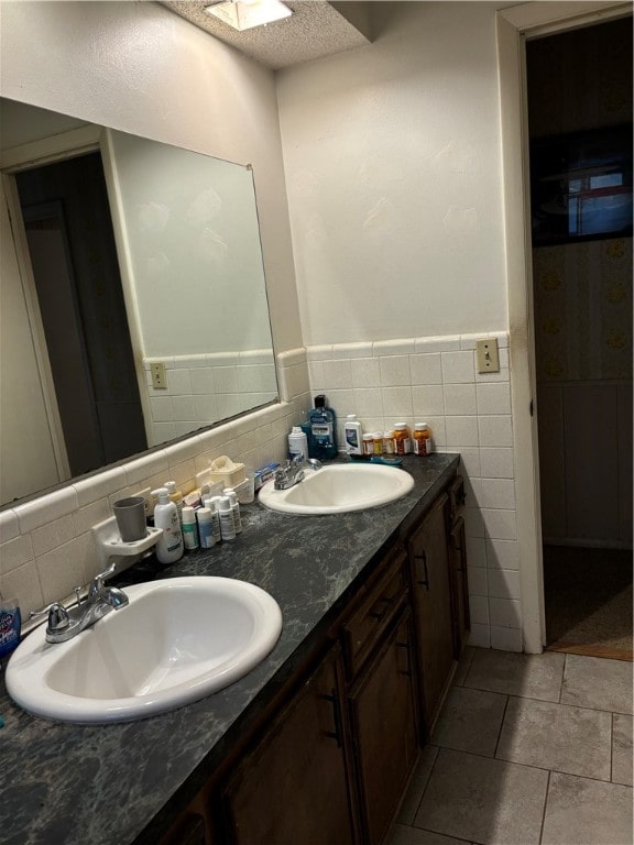 bathroom with tile walls, tile patterned floors, vanity, a textured ceiling, and a skylight