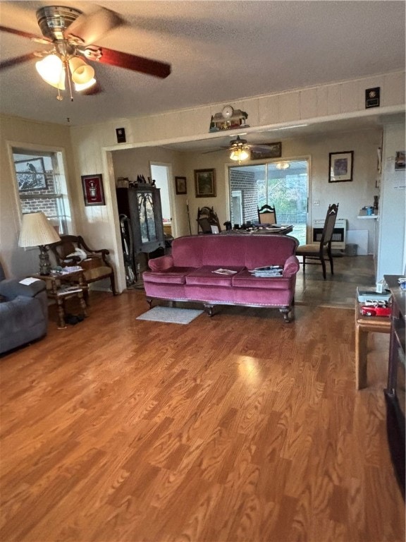 living room featuring hardwood / wood-style floors, ceiling fan, and a textured ceiling