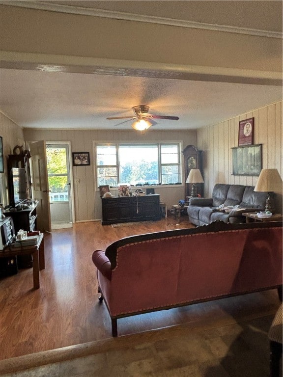 living room with hardwood / wood-style flooring, ceiling fan, and wooden walls