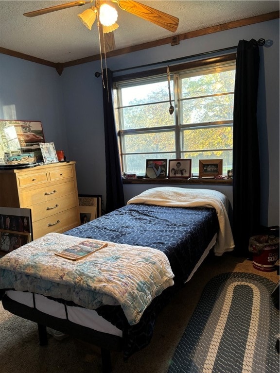 bedroom featuring ceiling fan, a textured ceiling, and ornamental molding