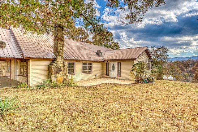 back of property featuring a mountain view and a yard