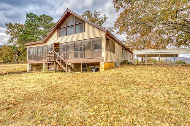 rear view of house with a carport, a yard, and a sunroom