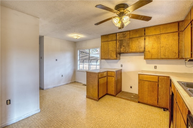 kitchen featuring a textured ceiling, ceiling fan, kitchen peninsula, and sink