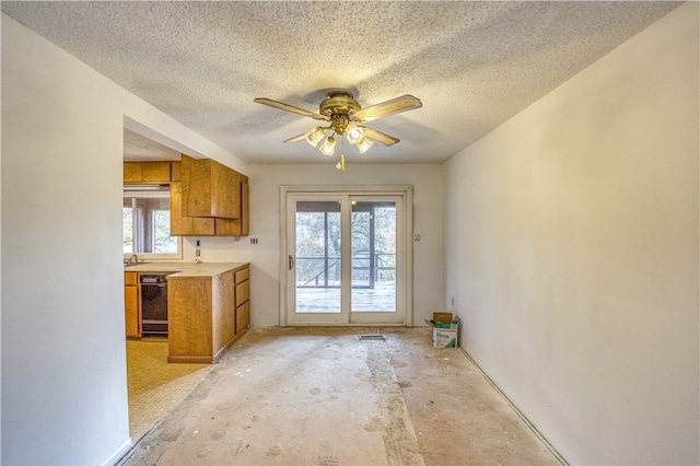 kitchen featuring a textured ceiling, ceiling fan, a wealth of natural light, and black dishwasher